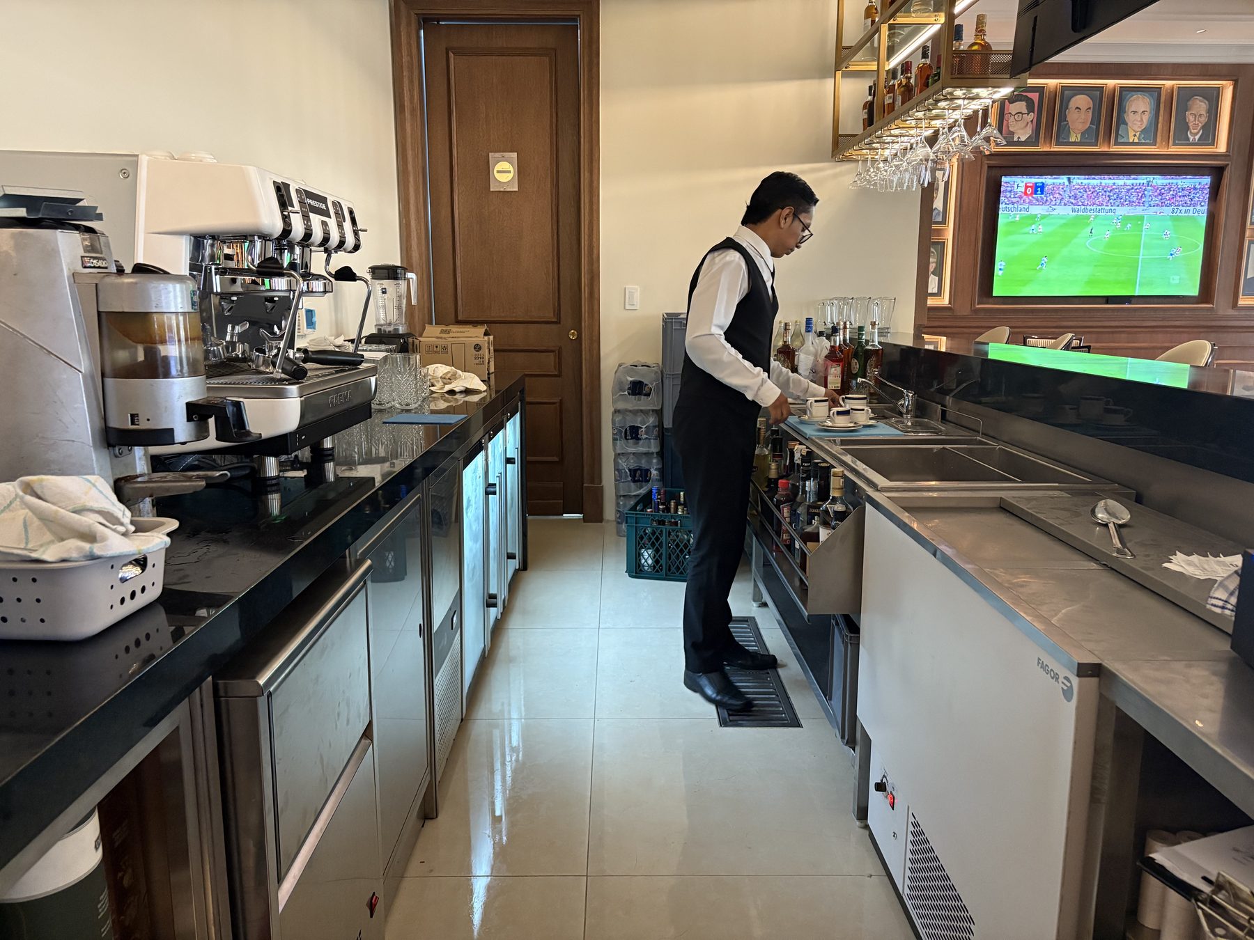 Área de equipos detrás de la barra con máquina de café y refrigeración bajo mesón