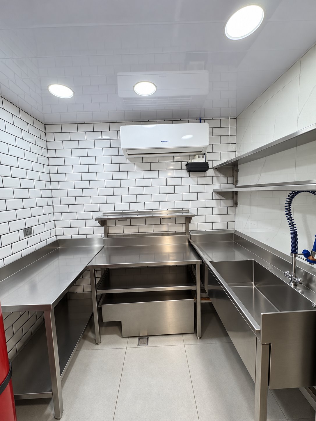 Área de preparación y lavado con mesas, repisas y lavadero de acero inoxidable