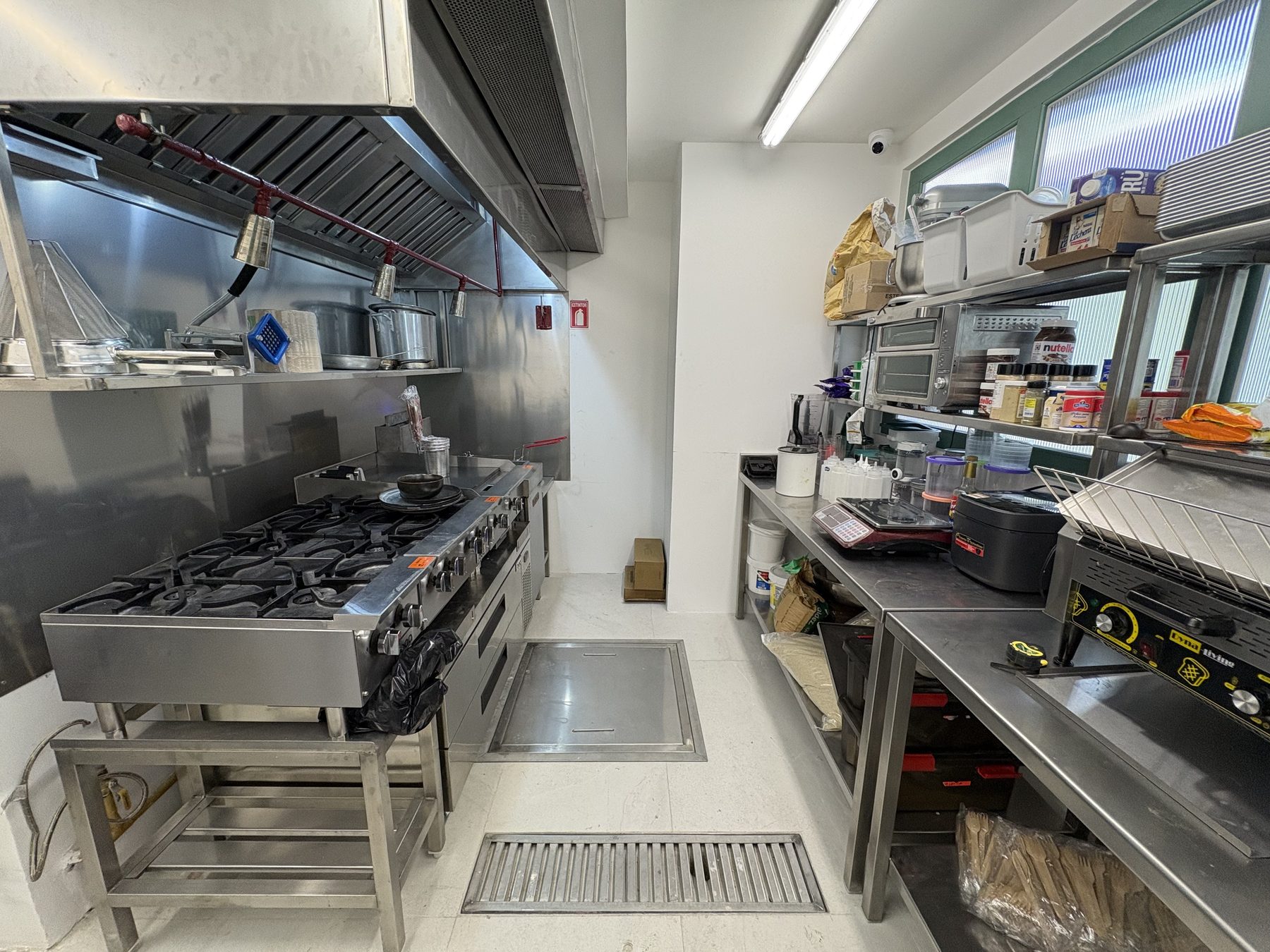 Vista general de la cocina de Ogui Neko: campana, recubrimiento de pared en acero, línea de cocción y mesas de trabajo