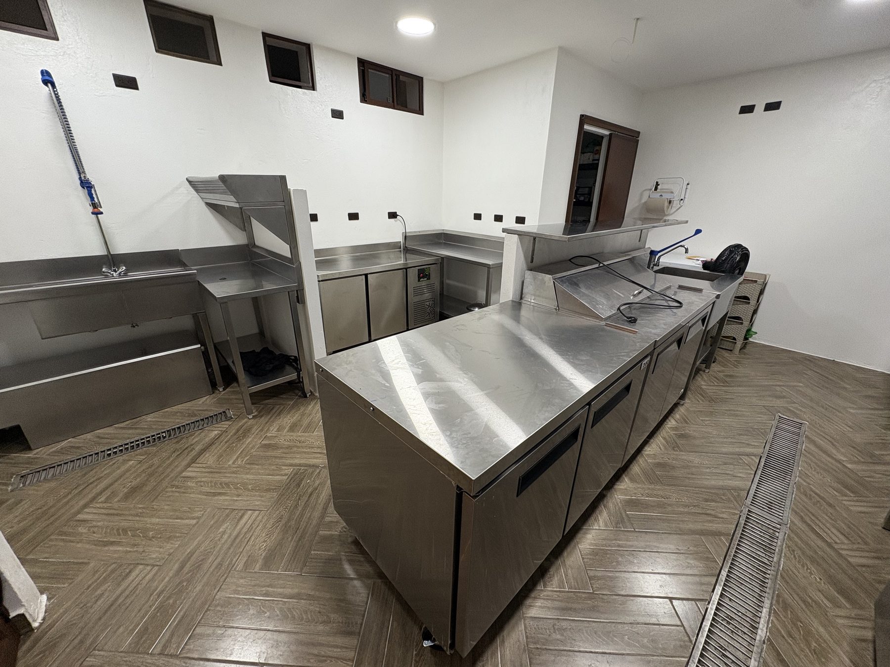Cocina de Ola Maruja con mesas refrigeradas, lavaderos y mesas de acero inoxidable