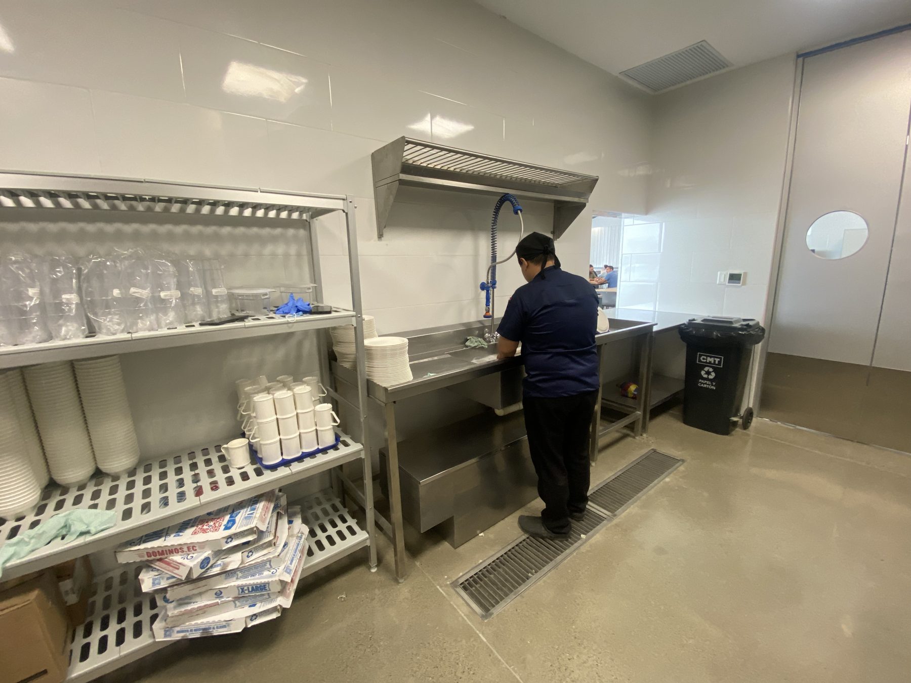 Zona de lavado con fregadero, ducha de prelavado y estanterías